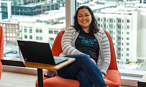 Image of a woman in front of a We Are Cisco neon sign