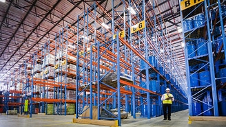 Employee takes inventory in a manufacturing warehouse